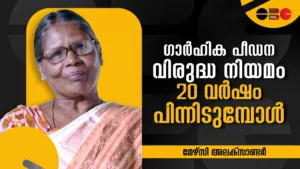 "ഗാർഹിക പീഡന വിരുദ്ധ നിയമം 20 വർഷം പിന്നിടുമ്പോൾ" എന്ന തലക്കെട്ടോടെയുള്ള ഒരു ചർച്ചാ വേദിയിലെ ചിത്രം. മൈക്കിന് മുന്നിൽ നിന്ന് സംസാരിക്കുന്ന ഒരു വനിതയെയും പശ്ചാത്തലത്തിൽ ഗൗരവത്തോടെ കേട്ടിരിക്കുന്ന സദസ്സിനെയും കാണാം. മുകളിൽ വലതുവശത്തായി 'OBC' ലോഗോ നൽകിയിരിക്കുന്നു.