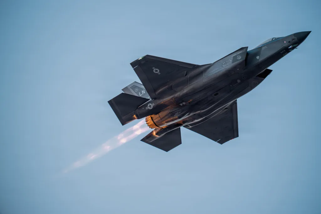 A Lockheed Martin F-35 Lightning II in flight, with visible exhaust heat from its engine.