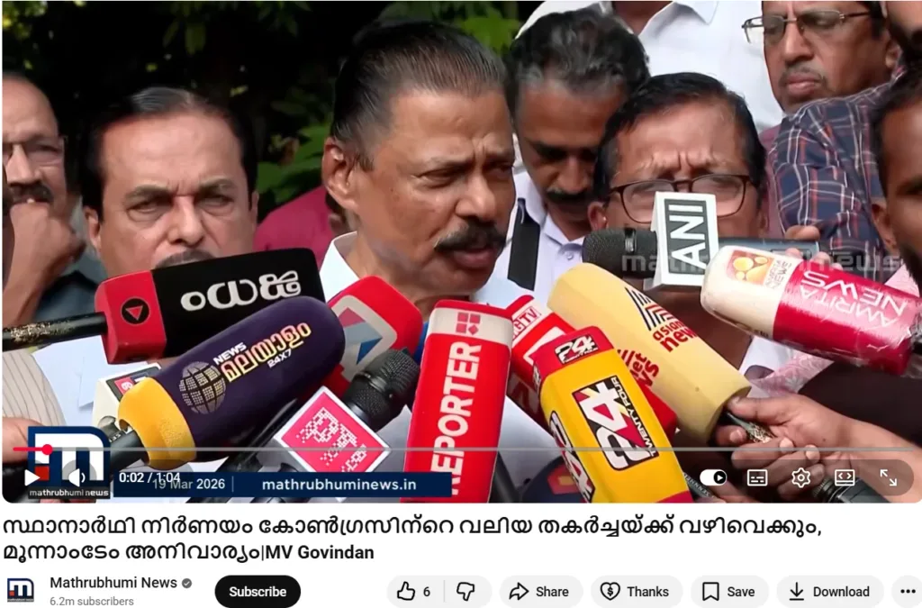 M. V. Govindan addresses the media outdoors, surrounded by microphones from Reporter, 24 News, Asianet News, ANI, and Mathrubhumi News. Greenery is visible in the background. Malayalam text quotes his comments about Congress candidate decisions, with the Mathrubhumi News logo and date “19 Mar 2026.”