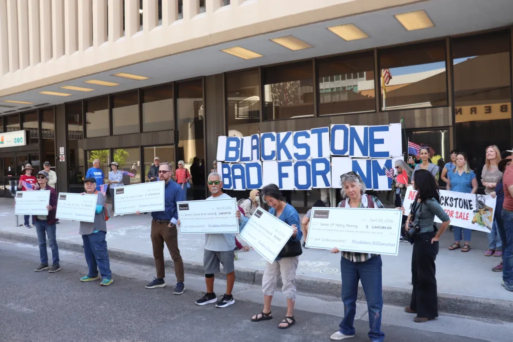 Protesters holding signs against Blackstone corporate housing exploitation during a demonstration in New Mexico