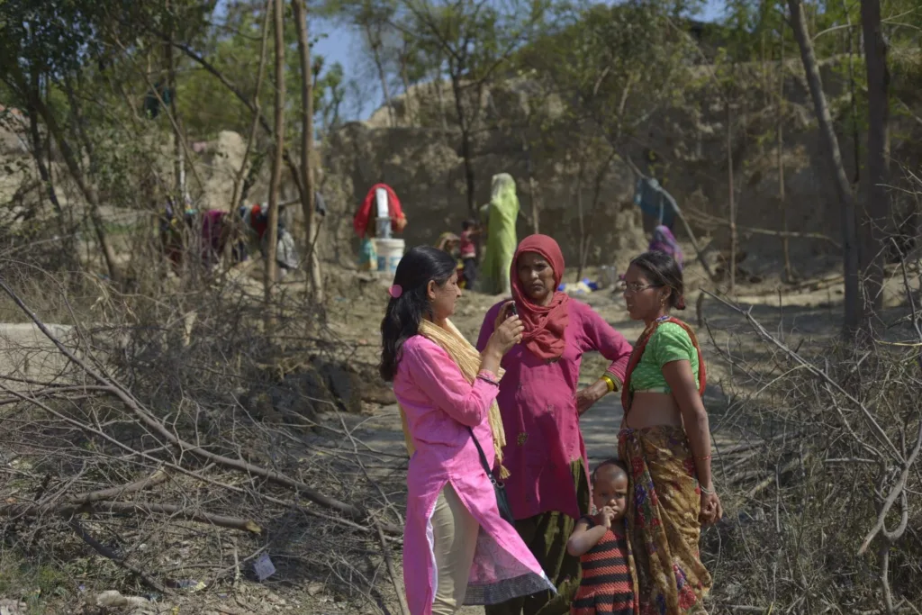 Khabar Lahariya journalist interacting with women and children in a rural Indian village.
