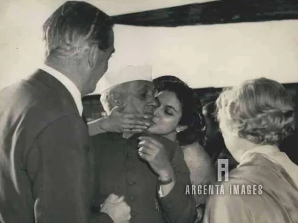 Historical black-and-white photograph of Jawaharlal Nehru being greeted with a kiss by his niece Nayantara Sahgal at London Airport in 1955, alongside Vijaya Lakshmi Pandit.